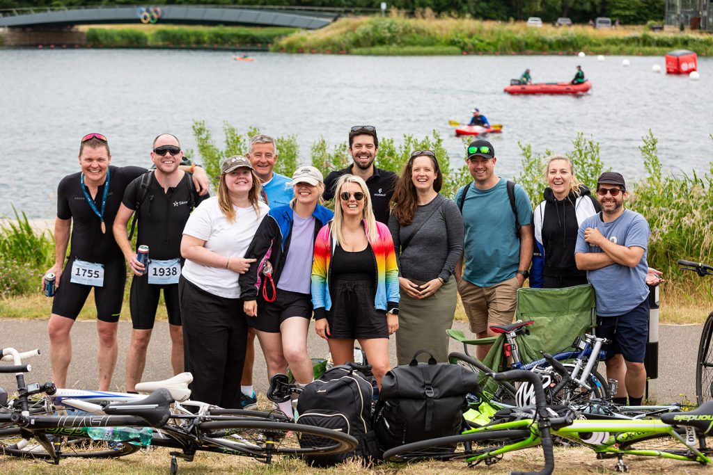 Group of employees standing in font of a lake at a triathlon event